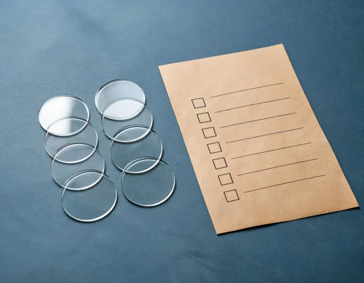 Glass lenses for eyeglasses blanks beside a project use checklist